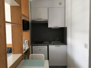 eine kleine Küche mit weißen Schränken und einem Waschbecken in der Unterkunft Studio Biarritz, 1 pièce, 2 personnes - FR-1-3-412 in Biarritz