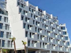a large white building with palm trees in front of it at Ekilibrio Hotel & Apart-Suites in Madrid