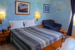 a hotel room with a bed and a chair at Hôtel La Palmeraie Saint Louis Sénégal in Saint-Louis
