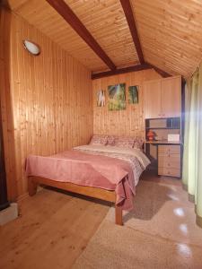 ein Schlafzimmer mit einem Bett in einem Holzzimmer in der Unterkunft Holiday House Trnovac in Trnovdc