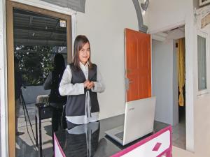 une femme debout devant une table avec un ordinateur portable dans l'établissement OYO 91826 Yoezef Homestay Syariah, à Pekanbaru