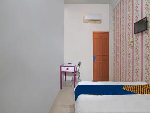 a room with two beds and a door and a table at OYO 91826 Yoezef Homestay Syariah in Pekanbaru