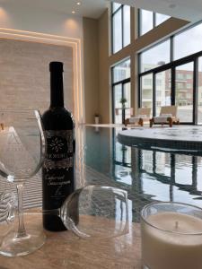 Una botella de vino sentada en una mesa junto a una piscina en Nordic Resort en Novi Sad