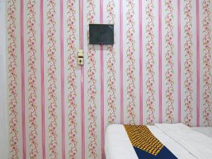 Schlafzimmer mit rosafarbener Tapete, einem Bett und einem TV in der Unterkunft OYO 91826 Yoezef Homestay Syariah in Pekanbaru