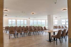 Habitación grande con sillas, mesas y ventanas. en Nordic Resort en Novi Sad