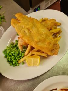 a plate of food with fish and fries and peas at The Crown Hotel in Inverbervie
