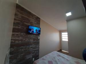 1 dormitorio con TV de pantalla plana en la pared en Uma agradável morada para descansar em Itapirubá! en Imbituba