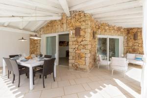 a dining room with a table and chairs and a stone wall at Villa Ginestra con piscina e giardino privato a 500 mt dal mare in Castiadas