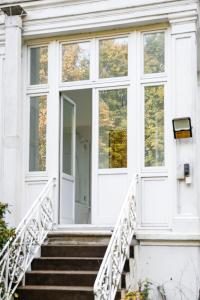 a white house with stairs and windows at Sleephotels Alsterroom in Hamburg