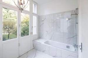 a white bathroom with a tub and a window at Sleephotels Alsterroom in Hamburg