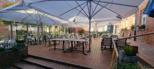 an outdoor patio with tables and chairs and umbrellas at Hohes Haus in Greetsiel