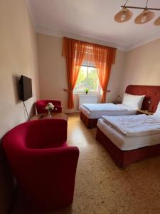 una habitación de hotel con 2 camas y una silla roja en Penzion Greenstar, en Ústí nad Labem