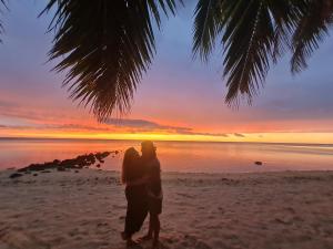 a man and woman standing on a beach at sunset at Sunny Beach Lodge in Amuri