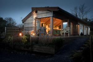 ein kleines Holzhaus mit einer Veranda und einer Terrasse in der Unterkunft Tyddyn Plwm Isa in Newborough