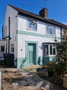 una casa blanca con una puerta azul en Summer, en Whetstone