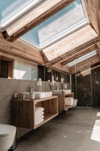 een badkamer met 2 wastafels en een dakraam bij Tanners Chalet Apartments in Altenmarkt im Pongau