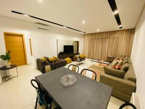 a living room with a couch and a table with chairs at Sousse Sahloul apartment de luxe 10 min de la mer in Sousse