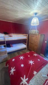 - une chambre avec 2 lits superposés et une couverture rouge avec des flocons de neige dans l'établissement APPARTEMENT COSY AUX SAISIES n1, aux Saisies
