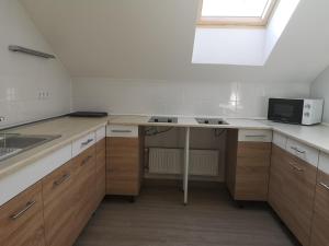 a kitchen with wooden cabinets and a table with a microwave at Ecostel Budaörs in Budaörs