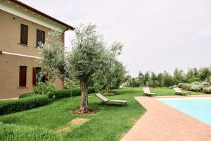 a garden with two benches and a tree next to a house at Il Casale degli Ulivi - Agriturismo - TENIMENTI LEONE in Lanuvio
