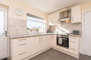 una cocina con armarios blancos y un reloj en la pared en City Home from Home - Peaceful, Cosy & Modern 2Bed house en Nottingham
