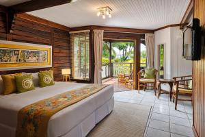 um quarto com uma cama grande e uma varanda em Acajou Beach Resort em Baie Sainte Anne