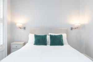 a bedroom with a white bed with two green pillows at Albert Rooms in Dublin