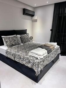 a bedroom with a black and white bed with pillows at Lagonisi Luxury Apartment by the sea in Lagonissi