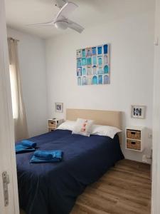 um quarto com uma cama azul e uma ventoinha de tecto em Casa Brisa Marina, en tranquilo pueblo costero. em La Mareta