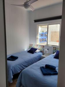 sypialnia z 2 łóżkami z niebieską pościelą i oknem w obiekcie Casa Brisa Marina, en tranquilo pueblo costero. w mieście La Mareta