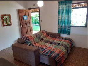 Un dormitorio con un sofá con una manta. en Casa das Violetas - Serra do Cipó, en Serra do Cipo