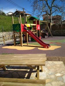 un parque infantil con tobogán y banco de madera en Apartamentos la Escuela en Cantabria, en Villegar