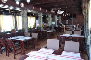 Pensiunea POPASUL CODRENILOR في Homorodu de Sus: مطعم بطاولات وكراسي خشبية في الغرفة