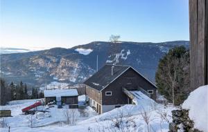 um celeiro na neve com montanhas ao fundo em Lovely Home In yer With House A Mountain View em Øyer