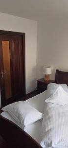 - une chambre avec un lit doté de draps blancs et d'une lampe dans l'établissement Apartament Slanic Moldova, à Slănic-Moldova