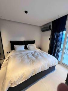 een slaapkamer met een groot bed en een groot raam bij Lagonisi 2 bedroom luxury Apartment by the sea! in Lagonissi