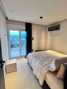 1 dormitorio con cama grande y ventana grande en Lagonisi 2 bedroom luxury Apartment by the sea!, en Lagonisi