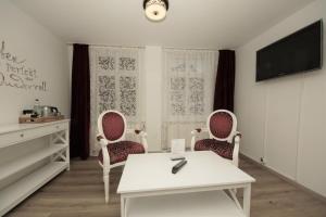 ein Wohnzimmer mit 2 Stühlen, einem Tisch und einem TV in der Unterkunft Liebezeit - ehemals Hotel Dillenburg in Dillenburg