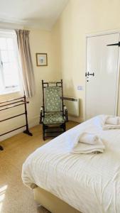 a bedroom with a bed and a chair and a window at Benwick Cottage - Beachfront Thatched Cottage set on the marine parade with absolutely spectacular Sea views! Sleeps 4 in Lyme Regis