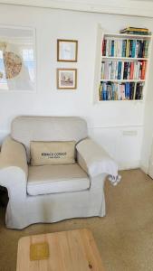 a white couch in a living room with a book shelf at Benwick Cottage - Beachfront Thatched Cottage set on the marine parade with absolutely spectacular Sea views! Sleeps 4 in Lyme Regis