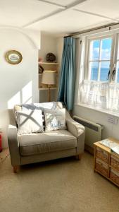 a living room with a couch and a window at Benwick Cottage - Beachfront Thatched Cottage set on the marine parade with absolutely spectacular Sea views! Sleeps 4 in Lyme Regis