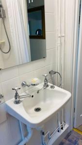 a bathroom with a white sink and a mirror at Benwick Cottage - Beachfront Thatched Cottage set on the marine parade with absolutely spectacular Sea views! Sleeps 4 in Lyme Regis +44 photos