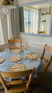 una mesa de comedor con platos y vasos. en Benwick Cottage - Beachfront Thatched Cottage set on the marine parade with absolutely spectacular Sea views! Sleeps 4, en Lyme Regis