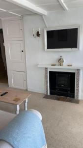 a living room with a tv and a fireplace at Benwick Cottage - Beachfront Thatched Cottage set on the marine parade with absolutely spectacular Sea views! Sleeps 4 in Lyme Regis