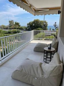 un porche con almohadas y una mesa en el balcón en Lagonisi Luxury appartment 2 by the sea en Lagonissi