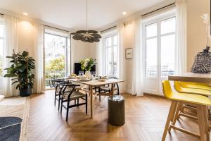 een eetkamer met een tafel, stoelen en ramen bij HYGGE KEYWEEK Apt 2 bedrooms with parking in Biarritz city center in Biarritz