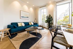 HYGGE KEYWEEK Apt 2 bedrooms with parking in Biarritz city center في بياريتز: غرفة معيشة مع أريكة زرقاء وطاولة