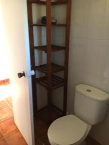 baño con aseo blanco y estanterías de madera en Agradable casa rural, en Murcia