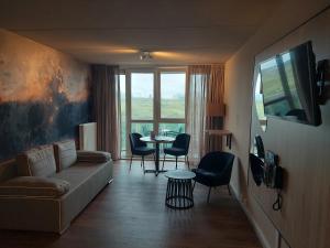 een woonkamer met een bank en een tafel met stoelen bij Fletcher Hotel Restaurant Zeeduin in Wijk aan Zee