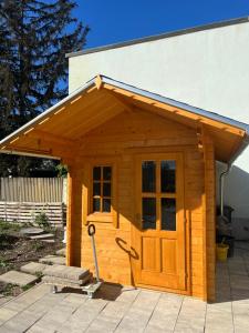 een houten buitenhuis met een deur in een tuin bij Ruhige Grüne Oase bei Flughafen Schwechat in Schwechat